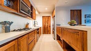 A modern kitchen with wooden cabinets, stainless steel appliances, and a white countertop. - Private Oceanfront Rooftop Plunge Pool & Beach Access (Huatulco)
