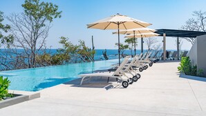 A poolside area with lounge chairs and umbrellas, overlooking a clear blue sea. - Private Oceanfront Rooftop Plunge Pool & Beach Access (Huatulco)
