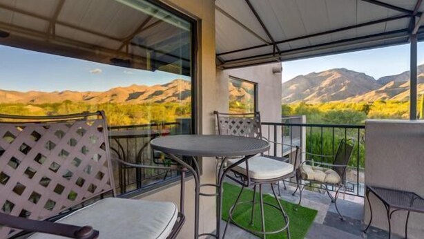A balcony with a table and chairs, offering a view of mountains and greenery. - Exquisite Greens condo with Breath taking views and exception interior (Tucson)
