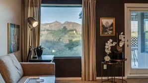 A room with a large window, a sofa, a lamp, a small table, and a potted plant. - Exquisite Greens condo with Breath taking views and exception interior (Tucson)