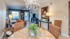 A hotel room with a dining area, a chandelier, a television, and a view of the outdoors. - Exquisite Greens condo with Breath taking views and exception interior (Tucson)