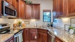 A kitchen with wooden cabinets, a granite countertop, a microwave, an oven, and a sink. - Exquisite Greens condo with Breath taking views and exception interior (Tucson)