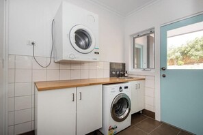 A laundry room with a washing machine and dryer, a wooden countertop, and a door with a window.