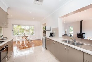 A modern kitchen with a dining area, large windows, and a built-in stove.