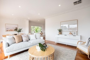 A modern living room with a white sofa, a round coffee table, and a white console table.