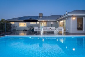 A modern house with a swimming pool, solar panels, and outdoor furniture.