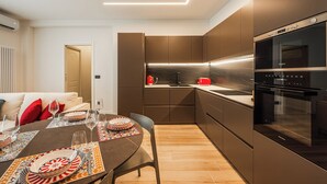 Una cuina moderna amb armaris foscos, forn integrat i zona de menjador amb taula preparada per a quatre.