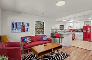 A modern living room with a red sofa, a wooden coffee table, and a zebra-patterned rug. - Downtown Historic Hideaway w/3 Adjacent Homes w/Fenced Yards, AC, W/D, Fast WiFi (Williams)