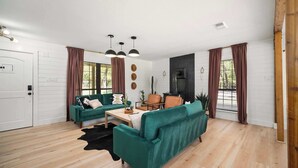 Een moderne woonkamer met een groene bank, een houten bijzettafeltje en een open haard.