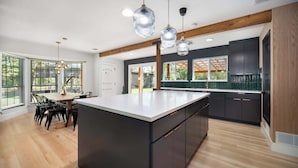 Een moderne keuken met een groot eiland, donkere kastjes en houten balken.