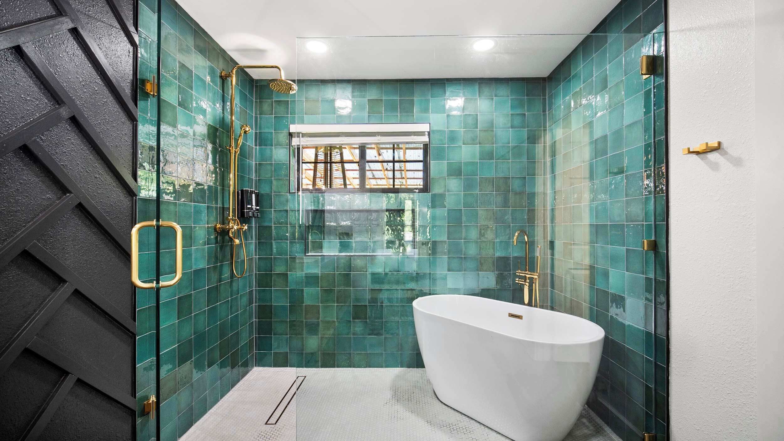 A modern bathroom with a freestanding bathtub, a shower with a gold showerhead, and a window with bars.