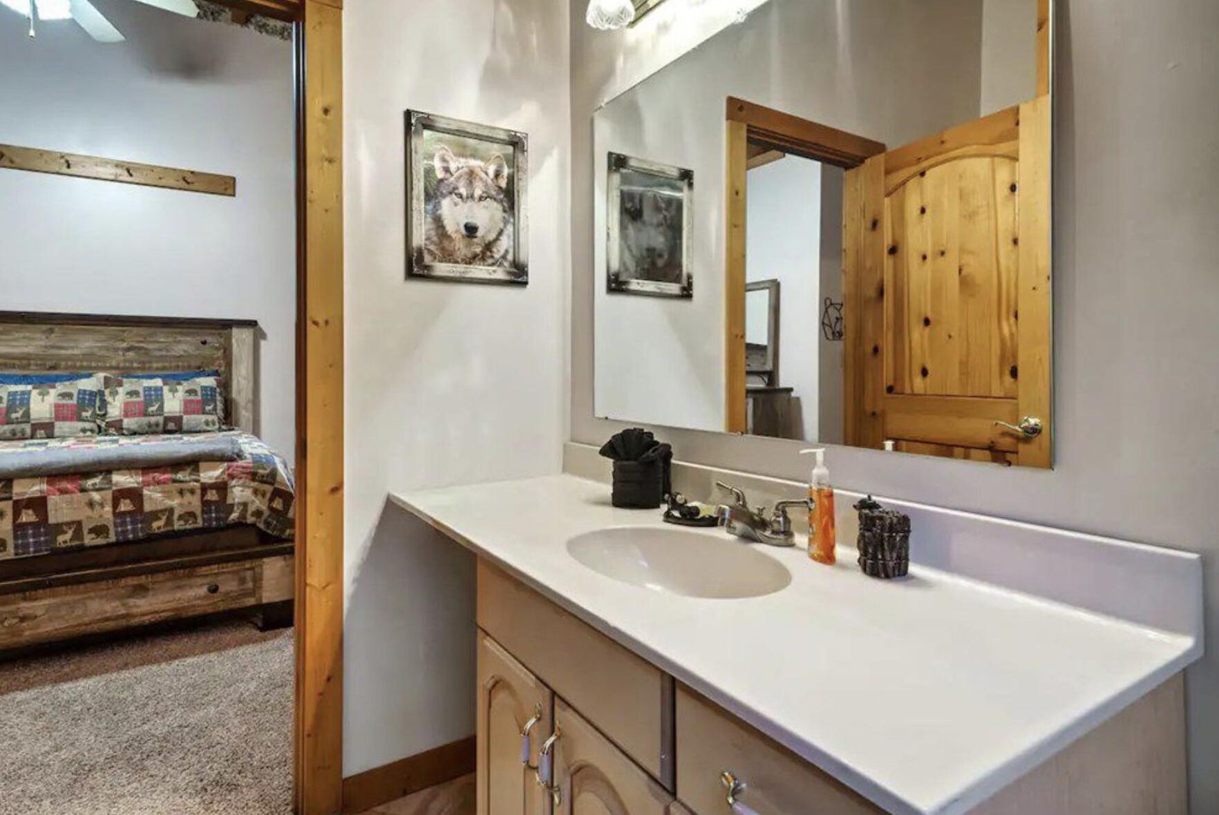 A bathroom with a large mirror, a sink, and a wooden cabinet.