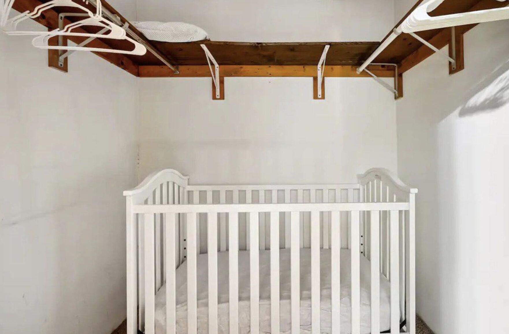 Un berceau blanc dans une pièce dont le plafond est en bois et les murs sont blancs.