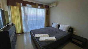 A hotel room with a bed, a dresser, and a window with curtains. - Apart hotel Gallery A
Апартамент в Слънчев Бряг на първа линия-гледка море (Слънчев бряг)