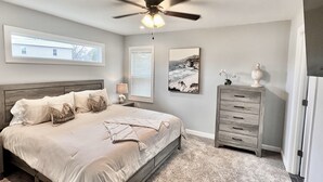Un dormitorio con cama, ventilador de techo, cómoda y ventana.