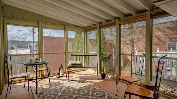 A sunroom with large windows, a wooden bench, a small table, and a patterned rug. - 30+ Day 3BR Home One Blk off Historic Main St. Galena w/Pking and W/D (Galena)