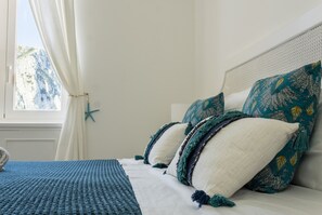 A bed with a white headboard, two pillows with a teal pattern, and a blue textured blanket.
