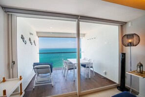Una habitación con puerta de vidrio corredera que da a un balcón con vistas al mar.