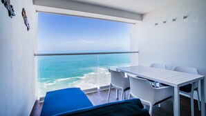 A balcony with a view of the ocean, a white table, and two white chairs. - 11th-Floor Oceanview Stay | Infinity Pools + Gym (Puerto Vallarta)