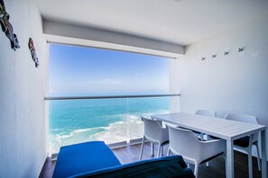 Un balcón con vistas al océano, una mesa y sillas.
