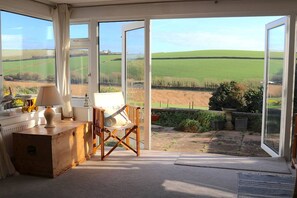 Ein Zimmer mit Blick auf ein grünes Feld durch große Glasüren.