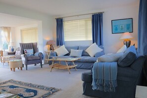 A living room with a sofa, armchair, coffee table, and a rug. - Sea Reach, Thurlestone, sleeps 8 (Thurlestone)