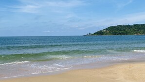 Une plage avec une eau d’un bleu limpide et un rivage sablonneux.