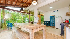 Une cuisine spacieuse avec une table et un banc en bois, de grandes fenêtres et une vue sur la verdure environnante.