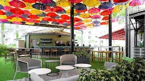 An outdoor seating area with round tables and chairs, a bar in the background, and colorful umbrellas overhead. - "2br At Meliá Orlando Celebration #528" (Celebration)