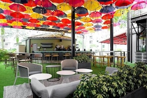 Um bar no terraço com área de estar ao ar livre, balcão e vista panorâmica da cidade.