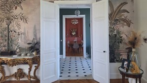 An open doorway leading to a dining area with a red wall, a chandelier, and a table with chairs. - Family manor house  (Bouchemaine)