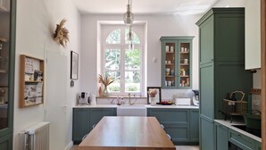 A kitchen with a central island, green cabinets, and a window with a view of greenery. - Family manor house  (Bouchemaine)