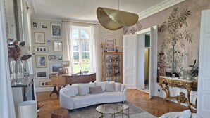 A spacious living room with a white sofa, a round coffee table, and a large hanging light fixture. - Family manor house  (Bouchemaine)