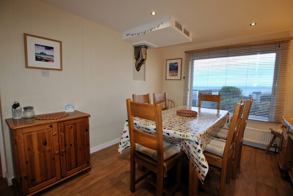 A dining area with a wooden table and chairs, a cabinet, and a window with blinds.