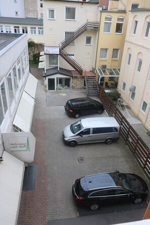 Ein Parkplatz mit drei Autos und einem Gebäude, das ein Hotel ausweist.