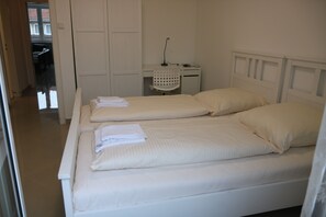 Ein Schlafzimmer mit zwei Betten, einem Schreibtisch und einem Stuhl.