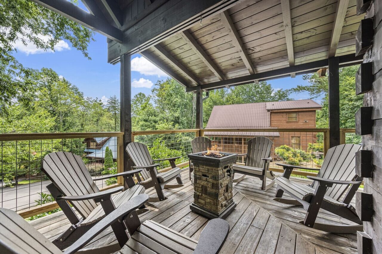 A wooden deck with Adirondack chairs and a stone fire pit.