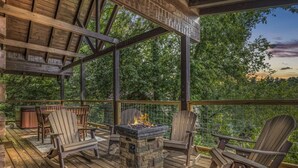 An outdoor deck with a stone fire pit, wooden chairs, and a table. - Near Attractions-Pool Table-Hot Tub-Fire Pit (Pigeon Forge)