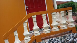 A red door with a white and orange staircase leading up to it. - Private Garden Villa in Manchester's Cool Highlands  (Cross keys)