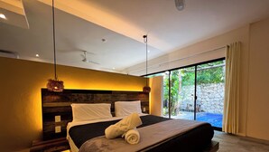 Une chambre moderne avec un grand lit, une tête de lit en bois et une vue sur un jardin, accessible par une porte-fenêtre coulissante.