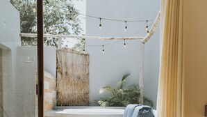 Une salle de bain moderne avec une douche à parois de verre, un banc intégré avec une serviette et une plante suspendue.