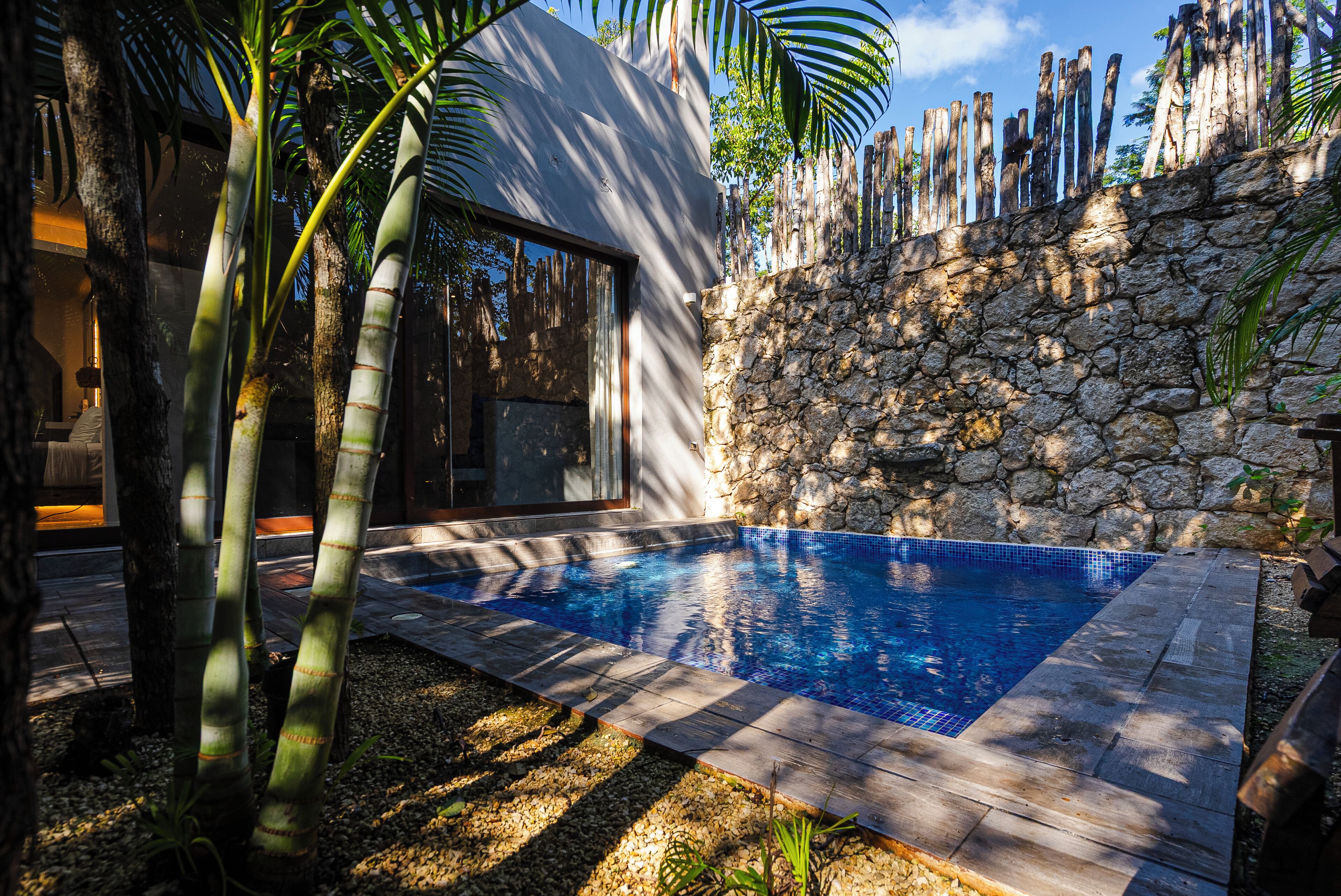 A swimming pool with stone walls and a modern house.
