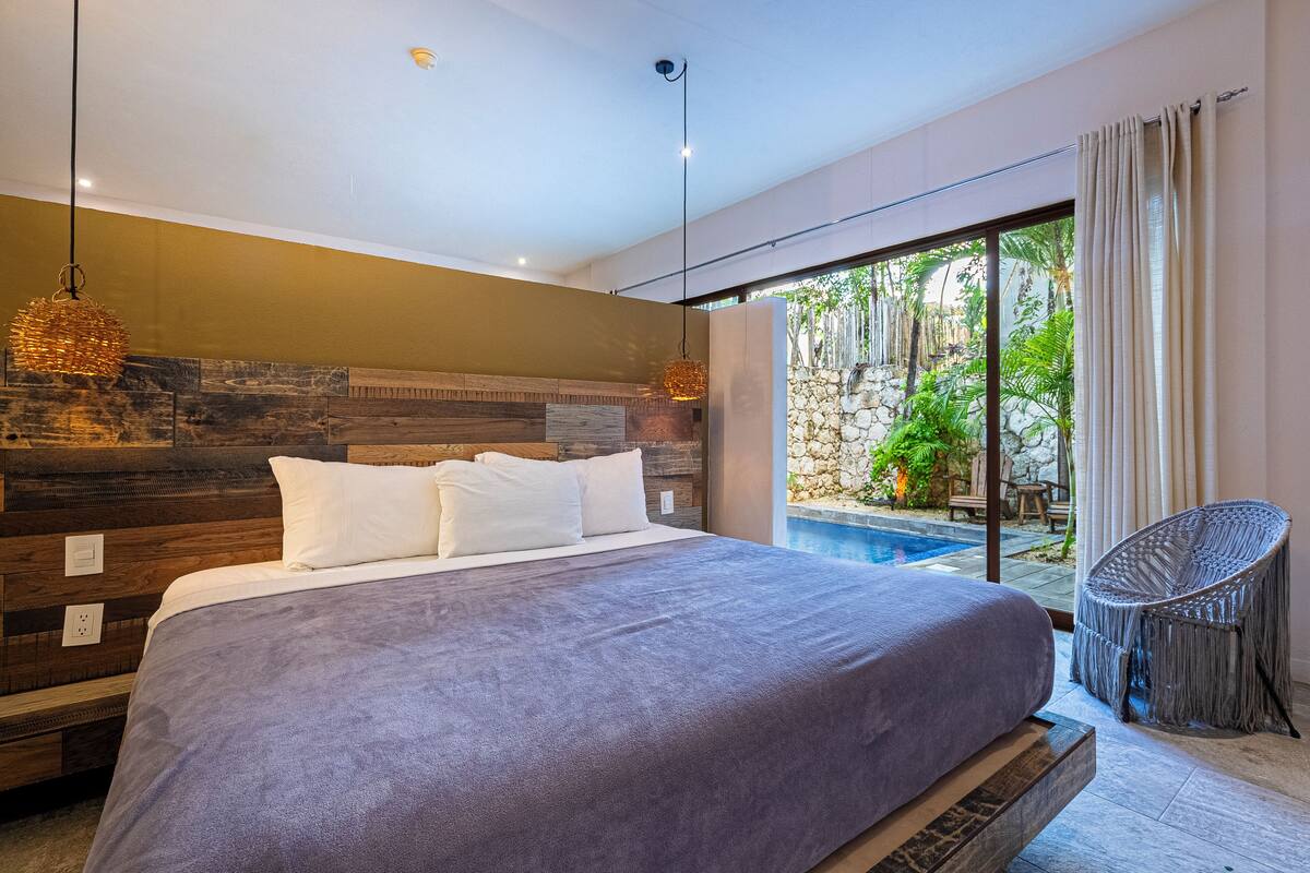 Un dormitorio moderno con una cama grande, una lámpara colgante y vistas a una piscina.