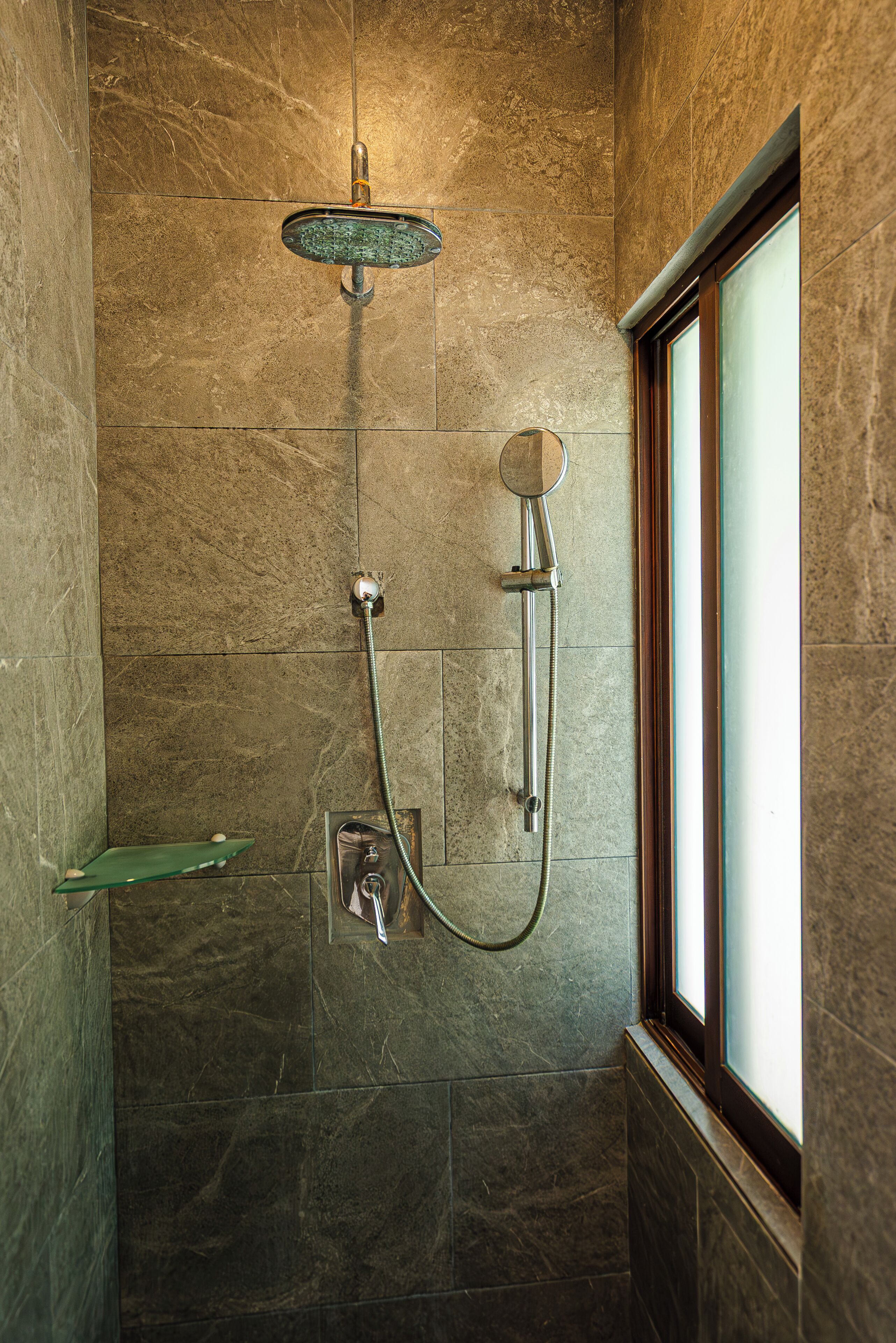 A shower with a handheld showerhead and a wall-mounted faucet.
