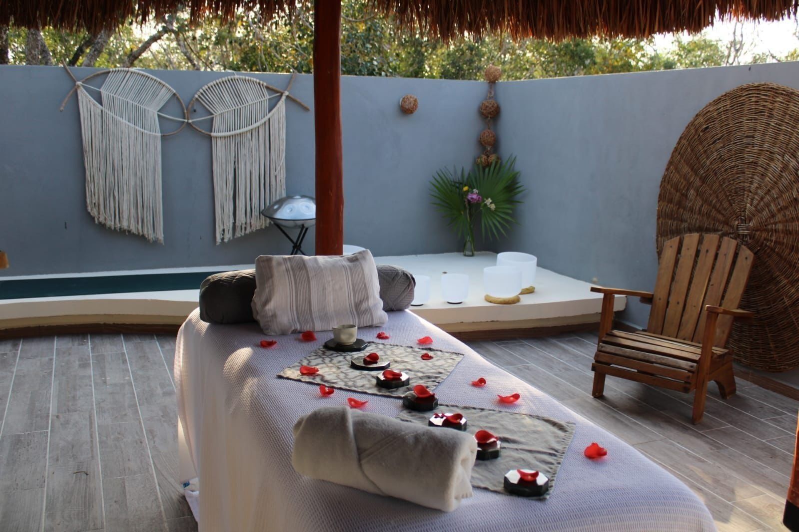 Een rustgevende spa-ruimte met een massagetafel, kussens, kaarsen en een houten stoel.