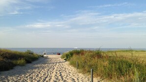 A sandy beach path leading to the sea with a boat in the distance. - Ferienwohnung mit Kamin am Achterwasser in Lütow (Lütow)