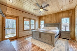 A wooden cabin bedroom with a bed, nightstands, and a ceiling fan.