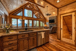 Una cocina espaciosa con una isla grande, vigas de madera en el techo y una chimenea de piedra.