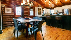 A wooden cabin interior with a dining area, kitchen, and bar. - The Rexford Cabin: Easy Drive to PA Grand Canyon! (Gaines Township)