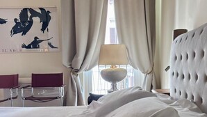 A hotel room with a bed, a chair, a lamp, and a painting on the wall. - Luxury suite off Piazza del Popolo (Roma)